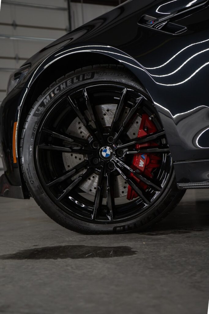 a close up of a black car with red spokes after having ceramic coating applied.